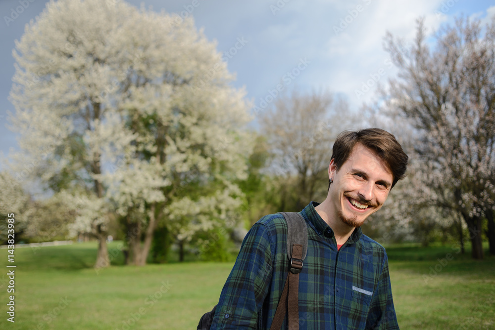 Young guy with a backpack in the park, green background Young guy with a backpack in the park, green background