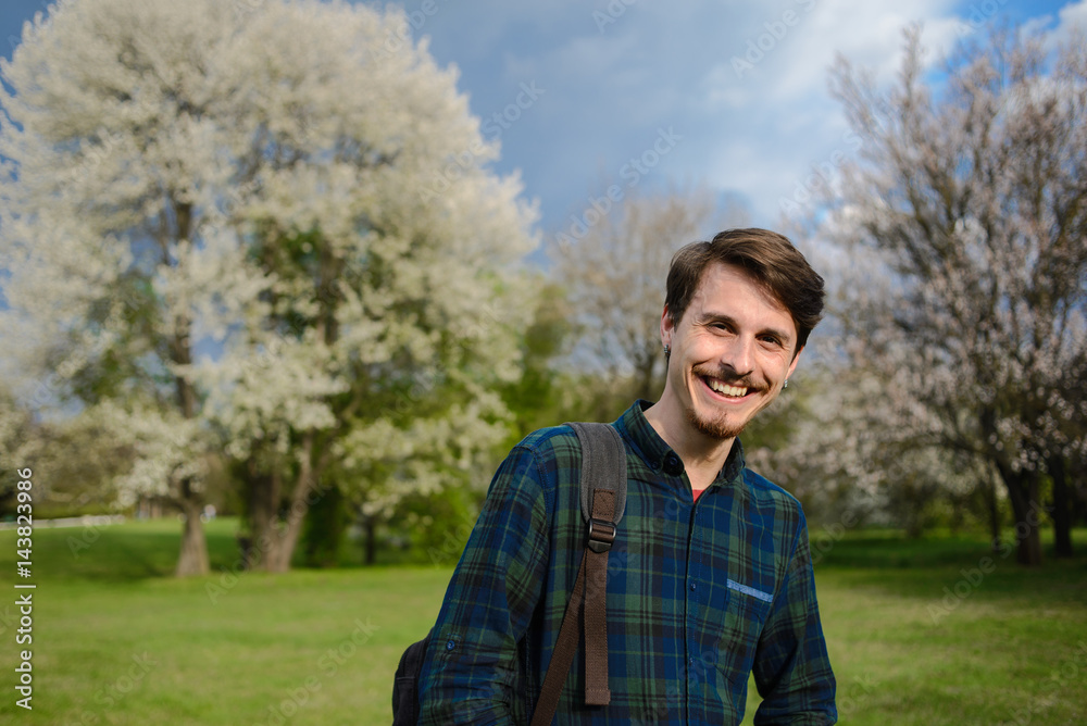 Young guy with a backpack in the park, green background