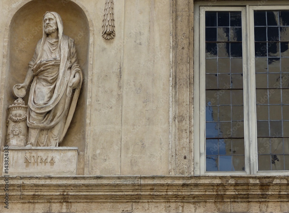 Statua di un filosofo greco accanto ad una finestra di un palazzo a Roma in Italia. Statua di un filosofo greco accanto ad una finestra di un palazzo a Roma in Italia.