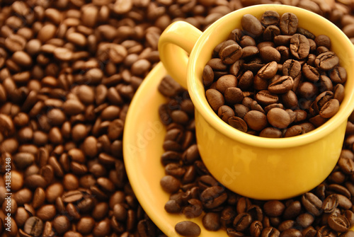 coffee beans in yellow cafe cup and background with coffee beans 