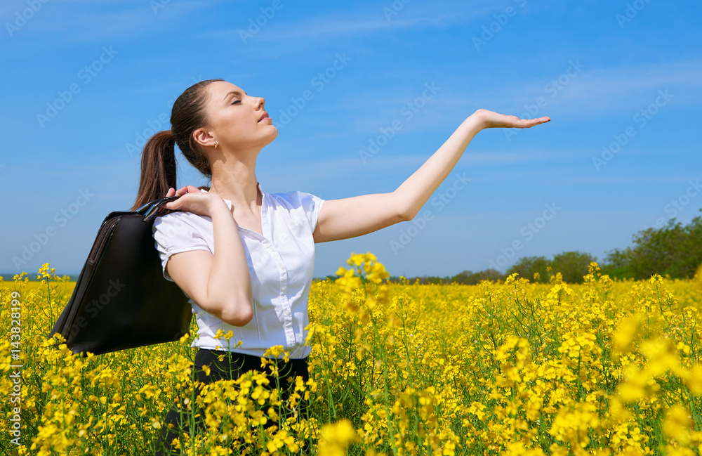 Business woman with briefcase show palm to sun. Young girl in yellow flower field. Beautiful spring landscape, bright sunny day, rapeseed Business woman with briefcase show palm to sun. Young girl in yellow flower field. Beautiful spring landscape, bright sunny day, rapeseed