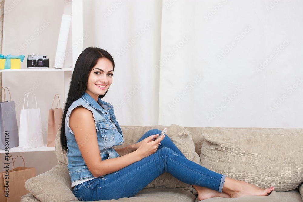 Happy girl reading a message in a smart phone sitting on a couch at home Happy girl reading a message in a smart phone sitting on a couch at home