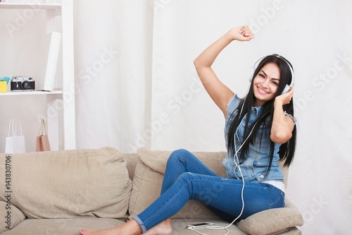One relaxed girl resting and listening music with headphones sitting on sofa photo