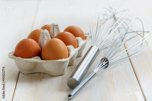 Box with brown eggs and beaters for whipping. photo