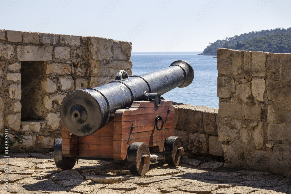 Ancient iron cannon on wooden mount on Dubrovnik stone rampart