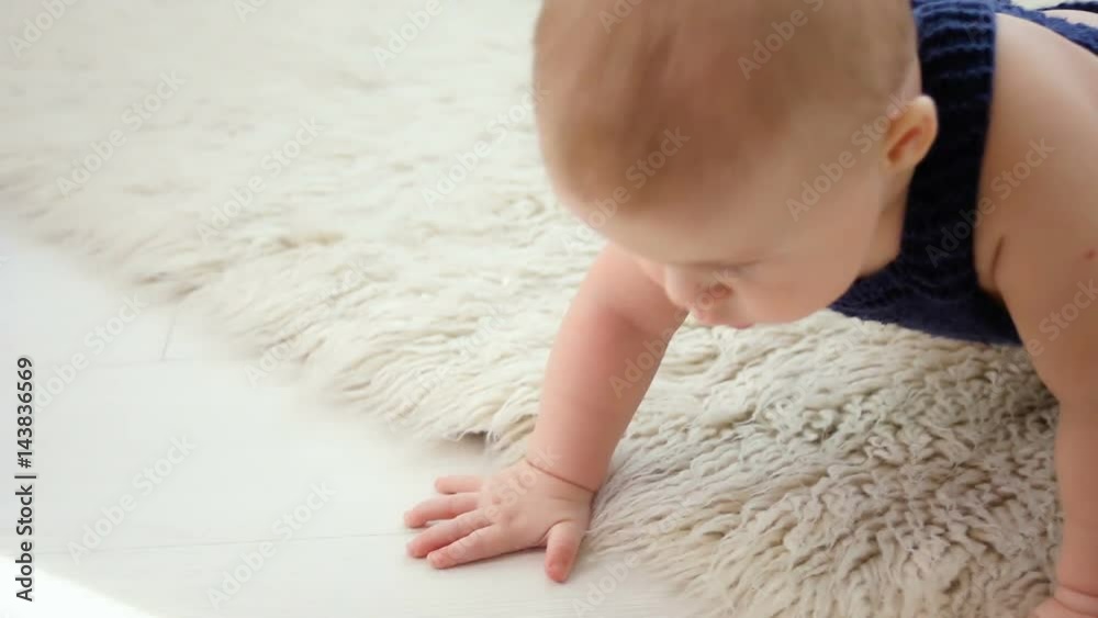 little baby boy of five months, crawling on the floor in the blue knit jumpsuit little baby boy of five months, crawling on the floor in the blue knit jumpsuit