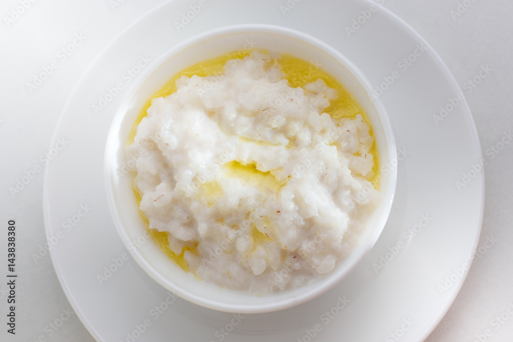 Healthy food - rice porridge with milk on a white plate Healthy food - rice porridge with milk on a white plate