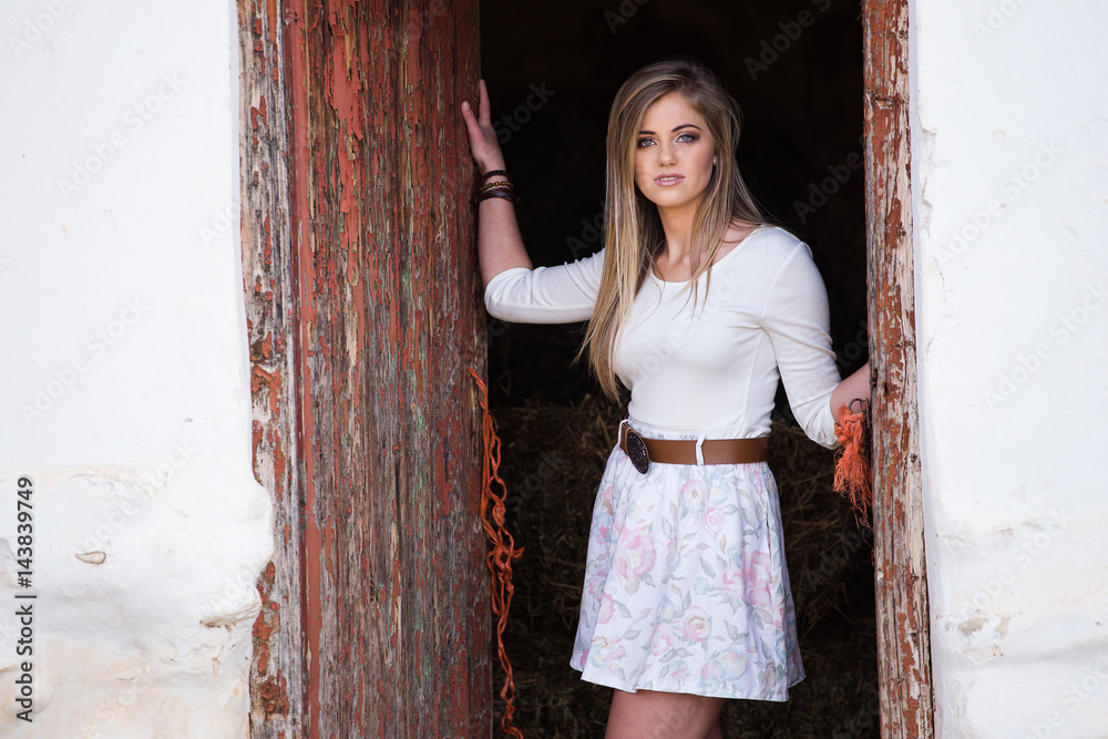 Senior photo of a young woman on a farm wearing farm style clothing Senior photo of a young woman on a farm wearing farm style clothing