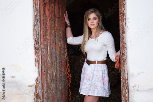 Senior photo of a young woman on a farm wearing farm style clothing