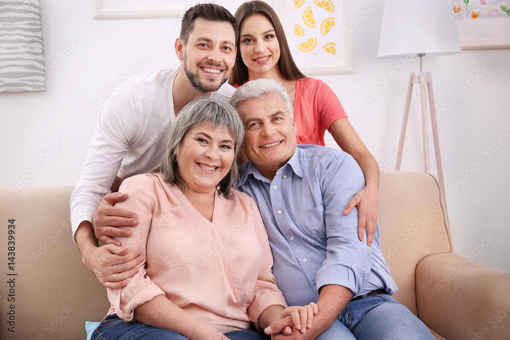 Young couple with middle aged parents on sofa in the room Young couple with middle aged parents on sofa in the room