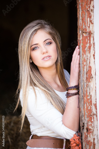 Senior photo of a young woman on a farm wearing farm style clothing