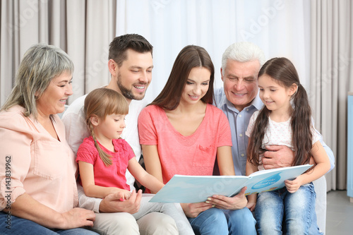 Happy family with book sitting on sofa in the room