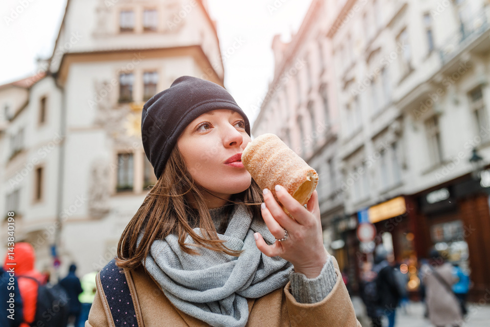 Woman eats Trdelnik on the street market in Prague, Czech Republic Woman eats Trdelnik on the street market in Prague, Czech Republic