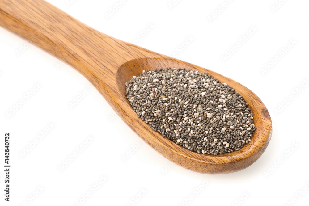 Whole dried black chai seeds in wooden spoon Whole dried black chai seeds in wooden spoon