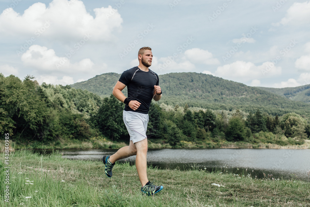 Male runner enjoying running across the country along a pond