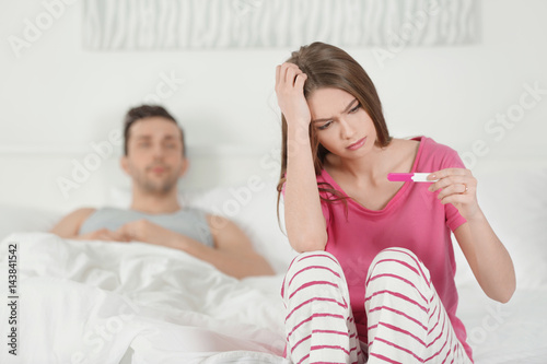 Upset wife sitting on bed a...