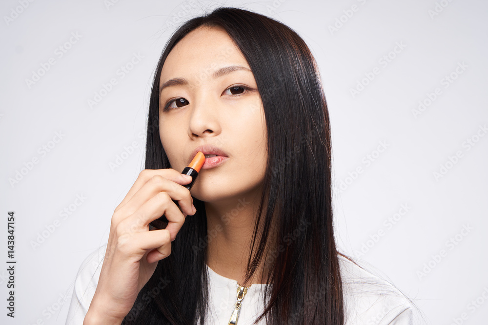 woman colors her lips, dark hair woman colors her lips, dark hair