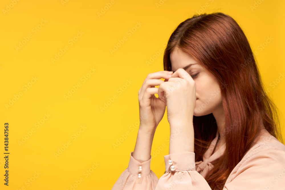 woman clasped her head, yellow background, side view woman clasped her head, yellow background, side view