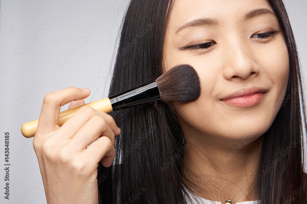 make-up brush in woman's hand, beautiful smile, dark hair make-up brush in woman's hand, beautiful smile, dark hair