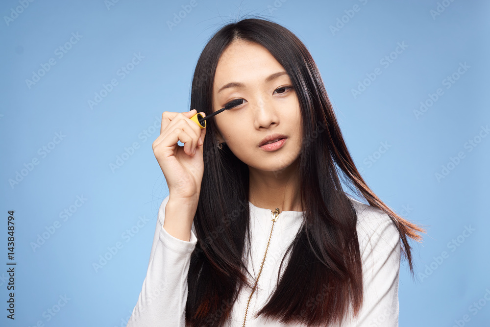 woman paints eyelashes with mascara for make-up woman paints eyelashes with mascara for make-up