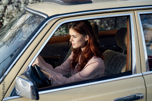 young woman with red hair behind the wheel of a car confident look...