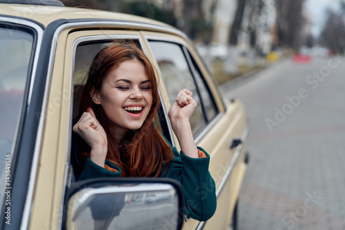 cheerful woman peeking out of car window, driver