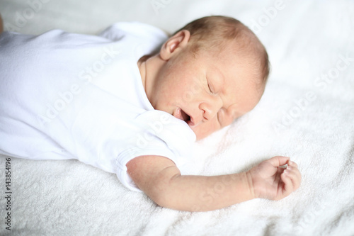 cute newborn baby sleeping peacefully on white blanket