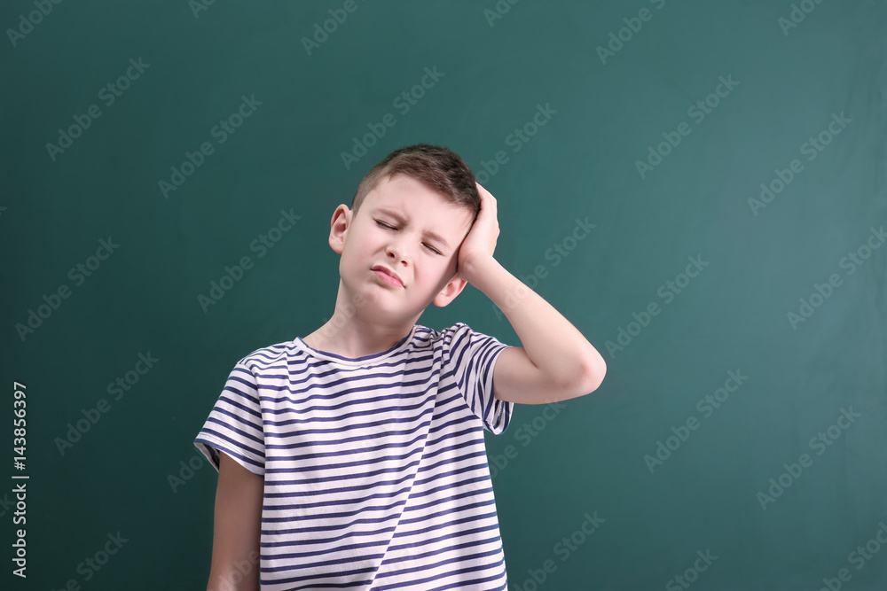Cute boy suffering from headache on color background Cute boy suffering from headache on color background