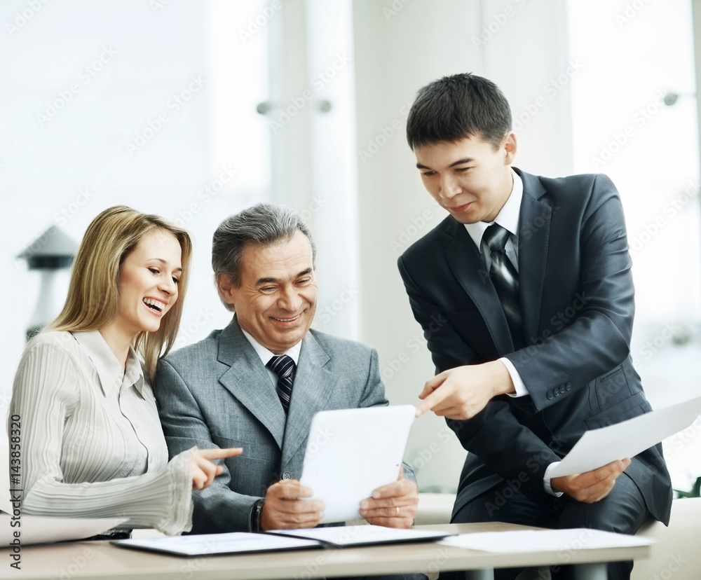 A successful business group discusses a work plan using a tablet A successful business group discusses a work plan using a tablet