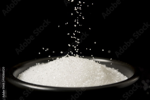 Sugar being poured to black bowl