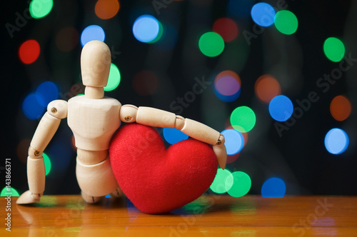 Wooden dummy hug red heart shape have bokeh as background
