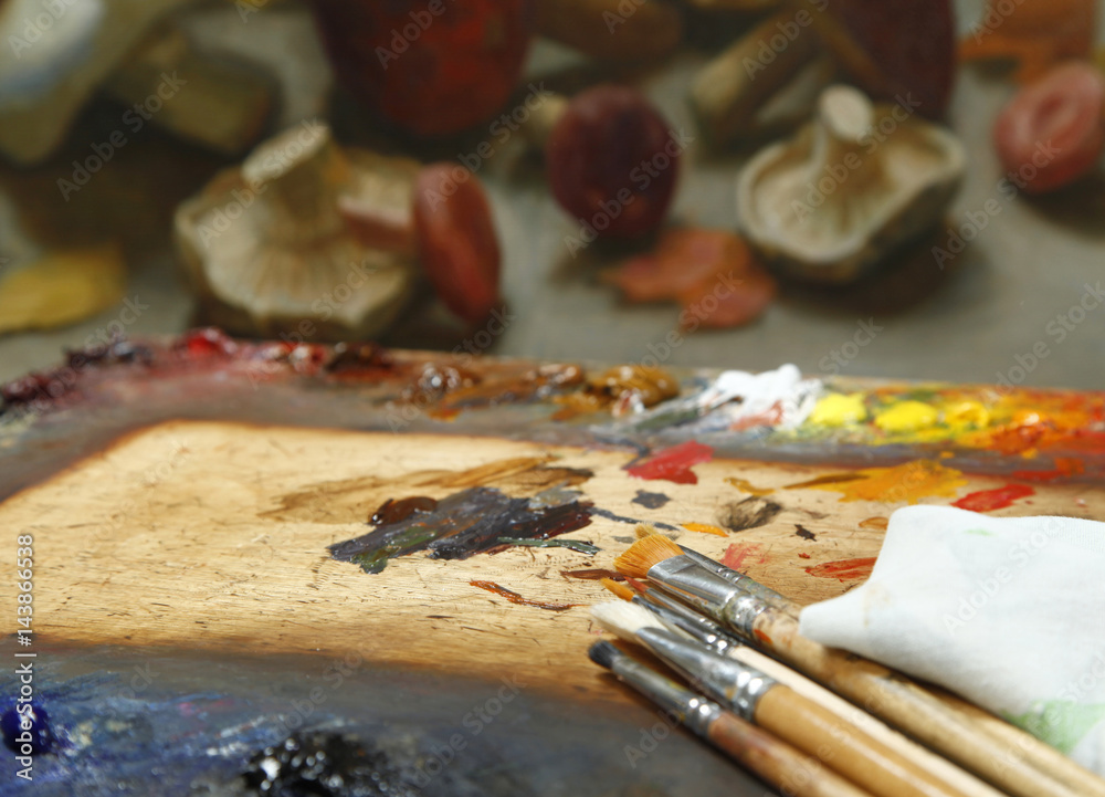 The workplace of the artist, brushes, paints and canvas. Multicolor oil paints on a palette close up.