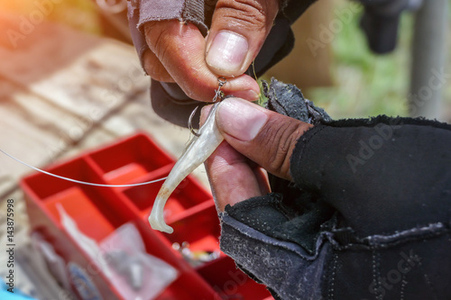 Photography Angler tying a fishing hook to rubber worm lure