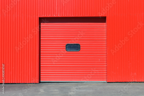 Red garage gate with small window on it. Large automatic up. Multicolor background set photo