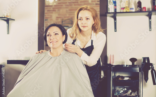 Woman is satisfied with work of young haircutter