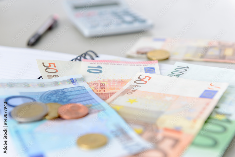 Euro money banknotes and coins counting with calculator, note book on desk