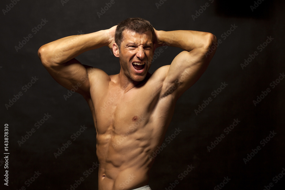 Fototapeta premium half-naked handsome and muscular young man posing on a dark background