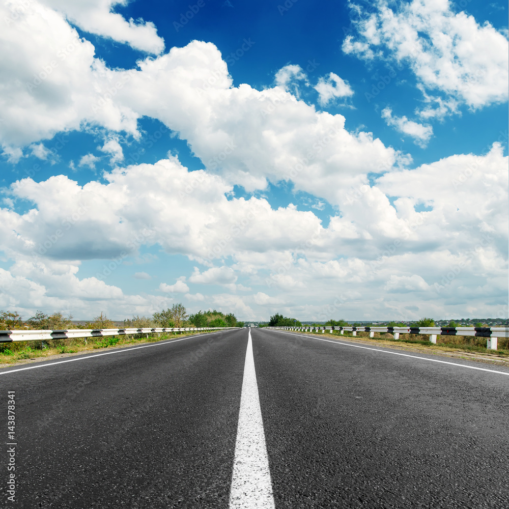 asphalt road to horizon and clouds in blue sky
