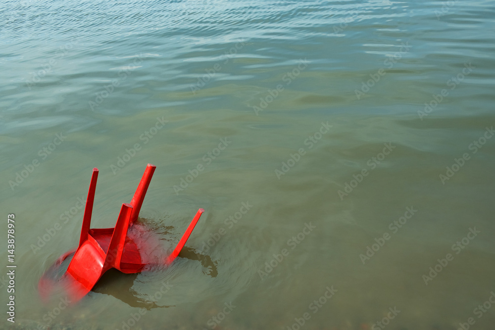 red plastic chair in the water red plastic chair in the water