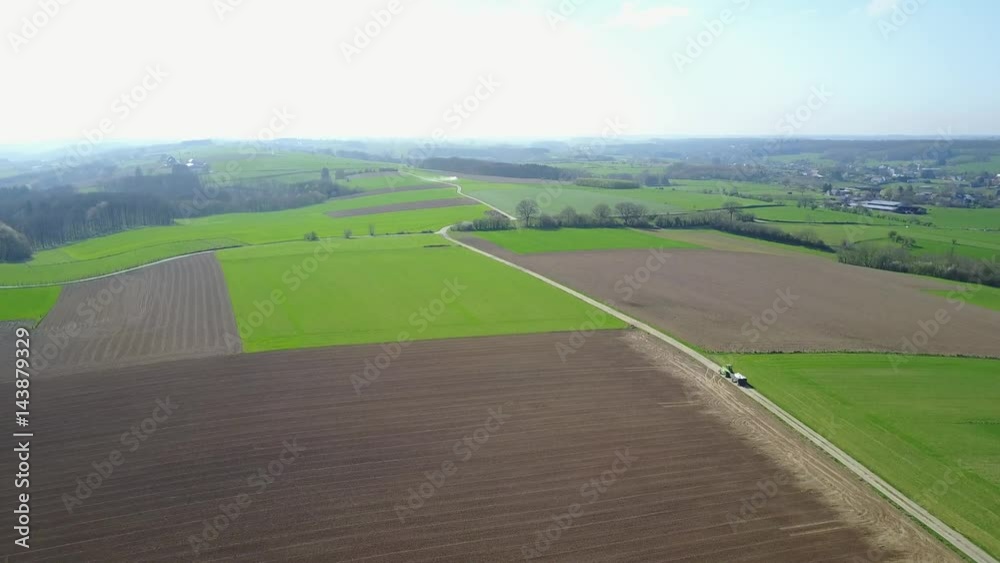 Aerial: tractor rides through the agrarian hilly fields in Somme-Leuze in Belgian Ardennes Aerial: tractor rides through the agrarian hilly fields in Somme-Leuze in Belgian Ardennes