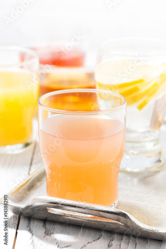 fresh citrus juices in glasses on white table, vertical
