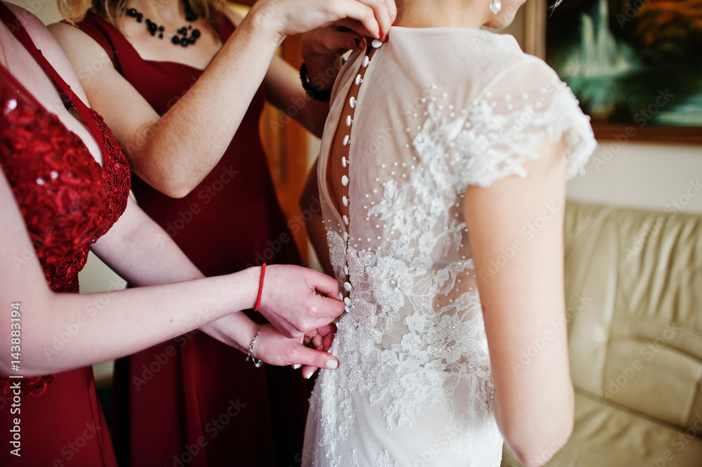 Bridesmaids helped wear bride dress in wedding morning.