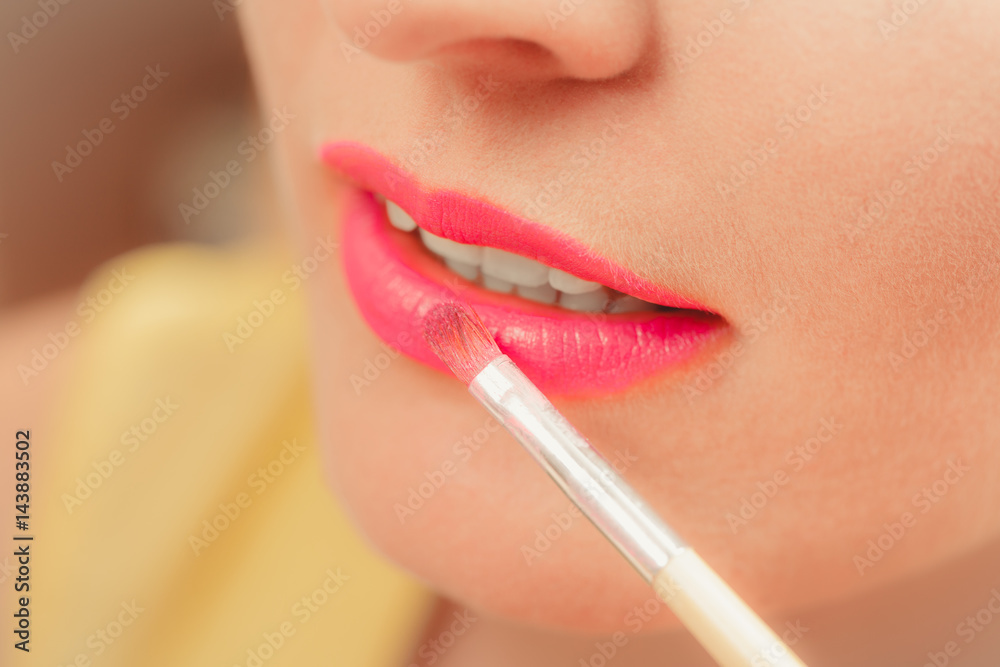 Woman applying lipstick with brush on lips. Makeup