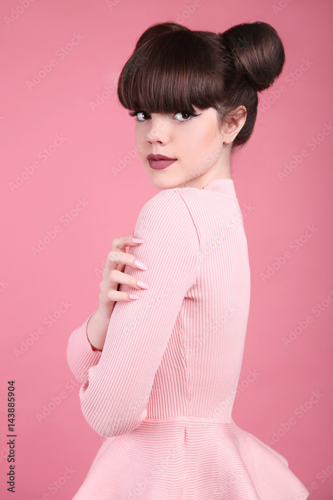 Teen beauty. Hairstyle. Fashion teenage girl model. Happy smiling Brunette with matte lips and funny hair style posing over studio pink background. Teen beauty. Hairstyle. Fashion teenage girl model. Happy smiling Brunette with matte lips and funny hair style posing over studio pink background.