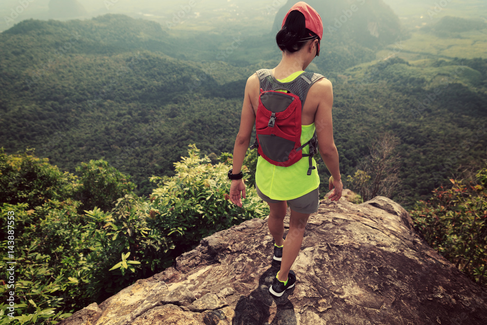 Obraz premium Young fitness woman trail runner running at mountain top