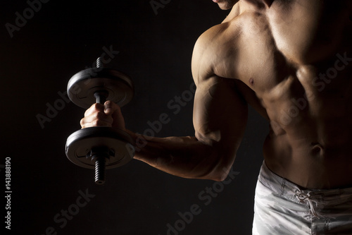 muscular man holding a weight on a dark background