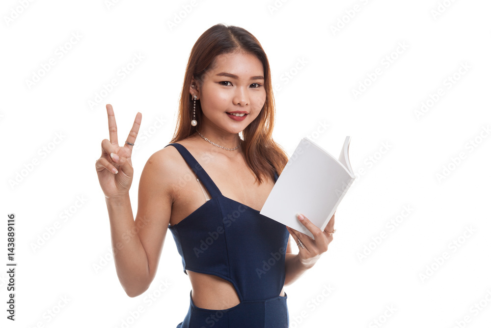 Young Asian woman show victor sign with a book. Young Asian woman show victor sign with a book.