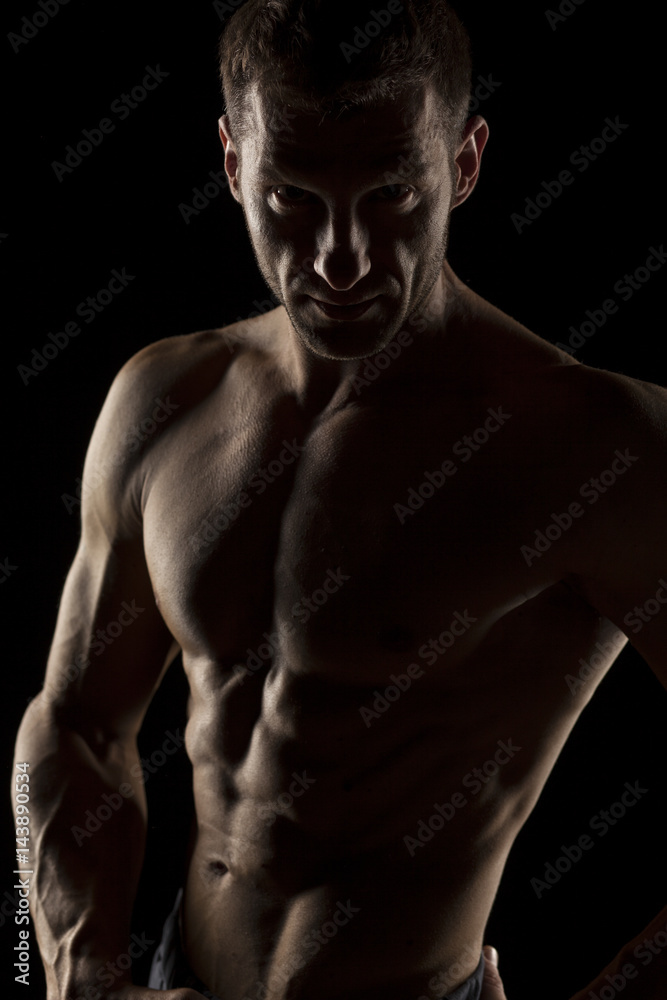 silhouette of half-naked handsome and muscular young man posing on a dark background silhouette of half-naked handsome and muscular young man posing on a dark background