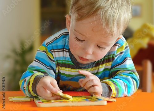 Little toddler doing puzzle. Boy learns to solve problems and develops cognitive skills and . Child concept. photo