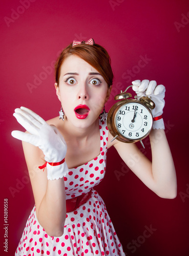 photo of beautiful young woman in vintage dotted dress with alarm clock on the wonderful burgundy background